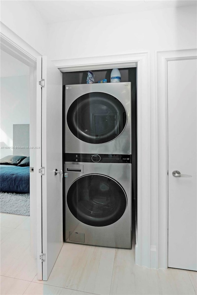 washroom with light tile patterned flooring and stacked washing maching and dryer