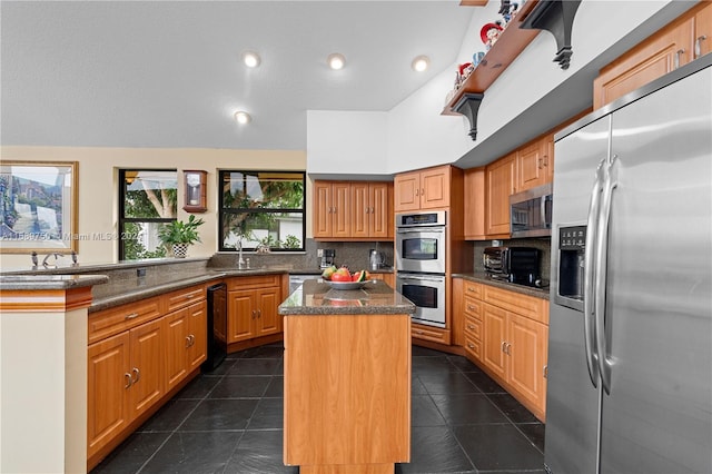 kitchen featuring backsplash, dark tile patterned flooring, sink, appliances with stainless steel finishes, and a kitchen island