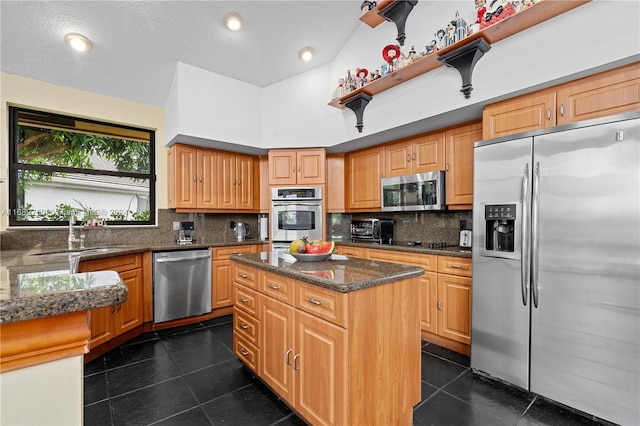 kitchen featuring a center island, backsplash, sink, a textured ceiling, and appliances with stainless steel finishes