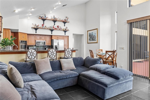 living room featuring dark tile patterned floors, high vaulted ceiling, and a textured ceiling