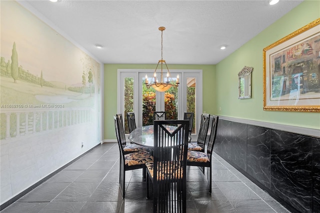 dining space featuring a textured ceiling, tile walls, and a notable chandelier