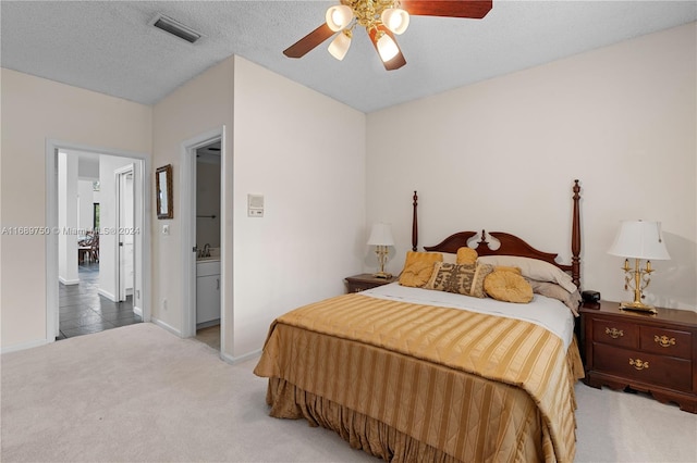 carpeted bedroom featuring a textured ceiling, ensuite bathroom, and ceiling fan