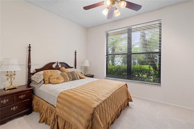 bedroom featuring a textured ceiling, light colored carpet, multiple windows, and ceiling fan