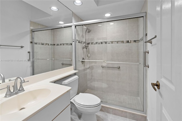 bathroom featuring tile patterned floors, vanity, a shower with shower door, and toilet