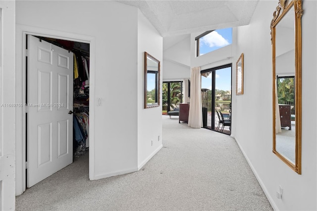 hallway featuring light colored carpet, a textured ceiling, and vaulted ceiling