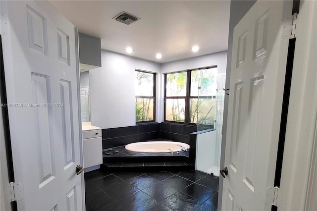 bathroom featuring vanity and tiled bath