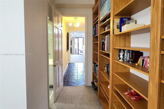 hallway with carpet flooring and a chandelier