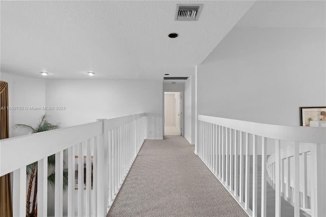 hall with a textured ceiling and light carpet