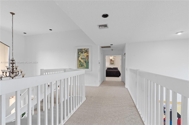 corridor with light carpet and a textured ceiling