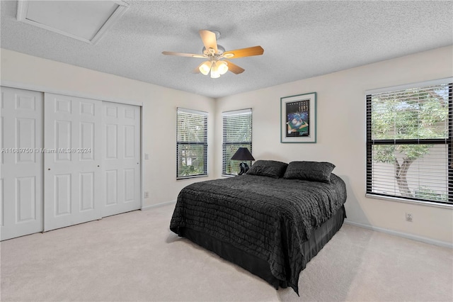 carpeted bedroom featuring multiple windows, ceiling fan, a closet, and a textured ceiling