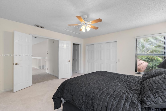 bedroom with ceiling fan, light carpet, and a textured ceiling