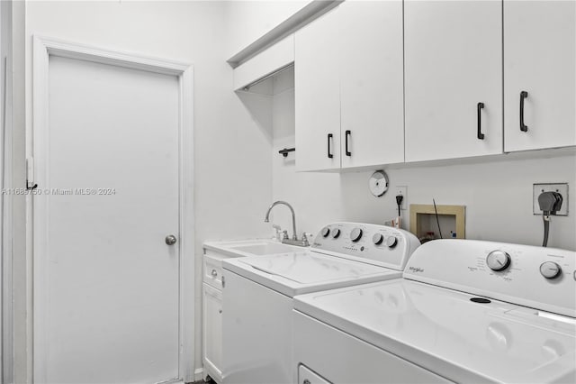 clothes washing area featuring separate washer and dryer, sink, and cabinets