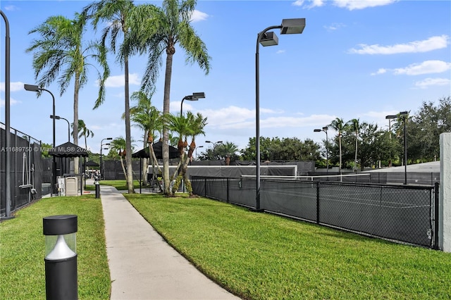 view of home's community with a lawn and tennis court