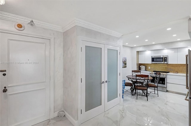 kitchen featuring french doors, white cabinets, crown molding, decorative backsplash, and stainless steel appliances