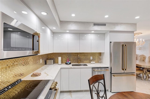 kitchen featuring decorative backsplash, light stone countertops, stainless steel appliances, sink, and white cabinetry