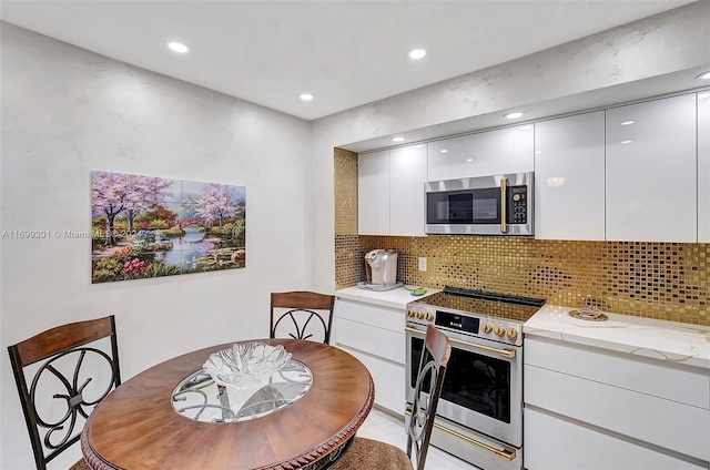 kitchen with decorative backsplash, stainless steel appliances, white cabinetry, and light stone counters