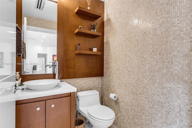 bathroom featuring vanity, toilet, and tile walls