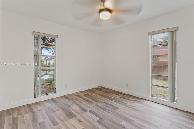 unfurnished room featuring ceiling fan, a water view, and light wood-type flooring