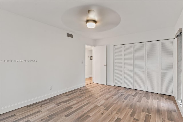 unfurnished bedroom with light wood-type flooring, ceiling fan, and a closet