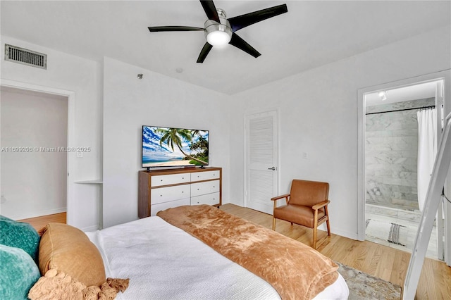 bedroom with light wood-type flooring, ceiling fan, and ensuite bathroom