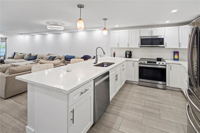 kitchen with hanging light fixtures, sink, kitchen peninsula, appliances with stainless steel finishes, and white cabinetry