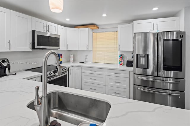 kitchen featuring white cabinets, light stone countertops, and stainless steel appliances