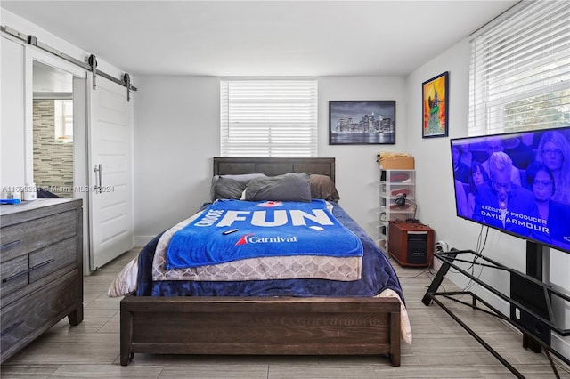 bedroom featuring a barn door and light hardwood / wood-style floors