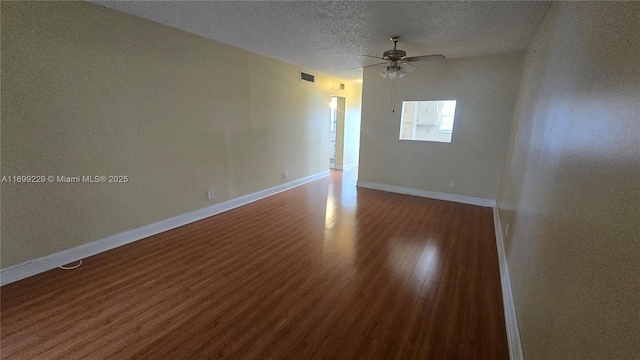 empty room featuring ceiling fan, a textured ceiling, baseboards, and wood finished floors