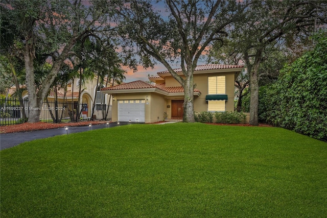 mediterranean / spanish-style home featuring a garage and a yard