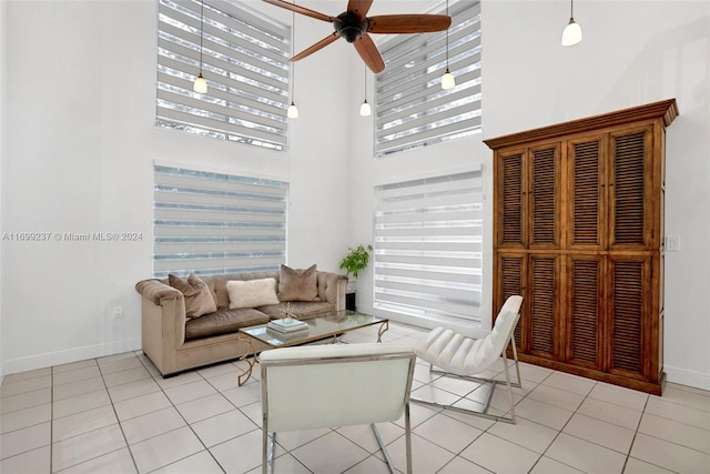 living room with light tile patterned floors, a towering ceiling, and ceiling fan