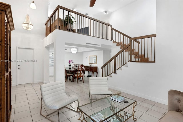 tiled living room with a towering ceiling and ceiling fan with notable chandelier