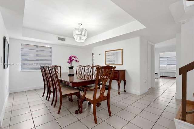 dining room featuring a tray ceiling and light tile patterned flooring