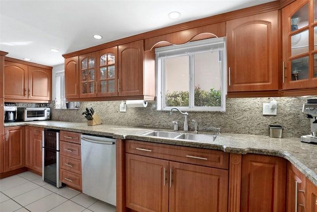 kitchen featuring light stone countertops, decorative backsplash, stainless steel dishwasher, and sink