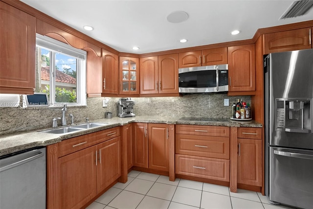 kitchen featuring backsplash, sink, light tile patterned floors, light stone countertops, and appliances with stainless steel finishes