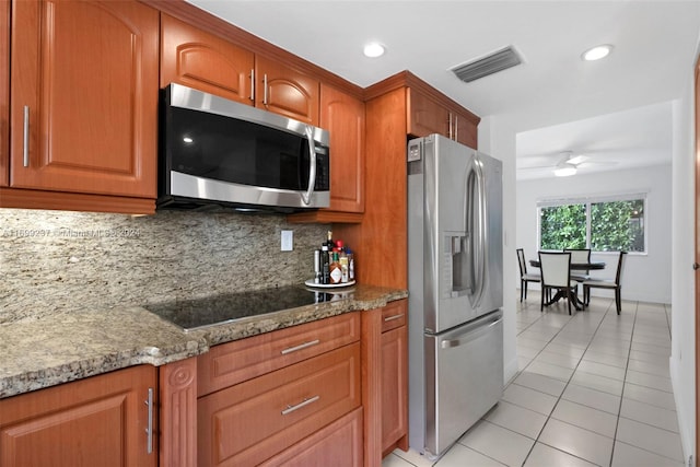 kitchen featuring appliances with stainless steel finishes, tasteful backsplash, light stone counters, ceiling fan, and light tile patterned floors