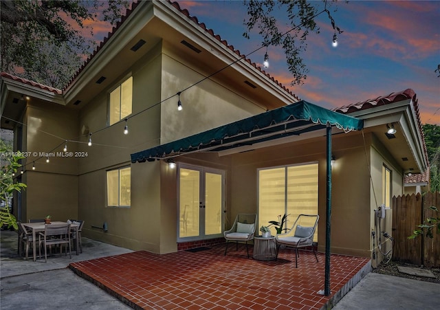 back house at dusk featuring a patio area and french doors