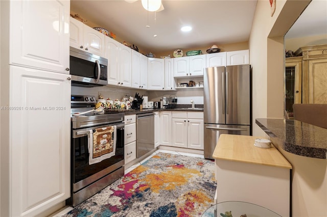 kitchen with white cabinets, sink, stainless steel appliances, and dark stone counters