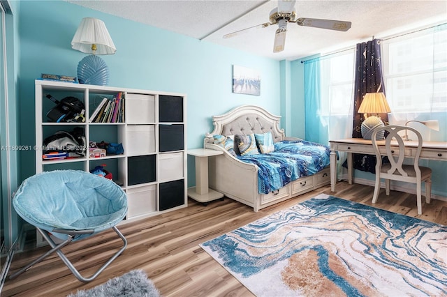 bedroom featuring ceiling fan, light hardwood / wood-style flooring, and a textured ceiling