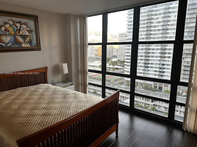 bedroom featuring a textured ceiling, dark hardwood / wood-style flooring, and a wall of windows