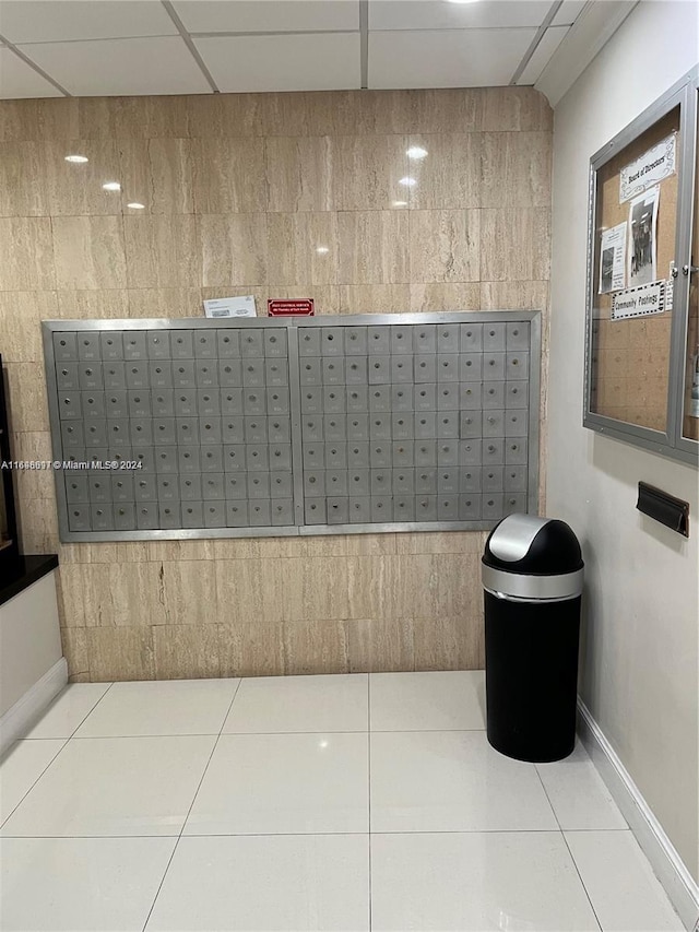 interior space with tile patterned flooring, a drop ceiling, mail boxes, and tile walls