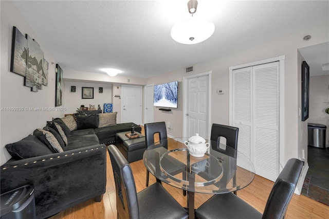 dining space with light hardwood / wood-style flooring and a textured ceiling