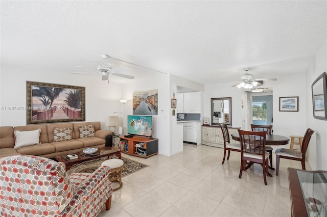 living room with ceiling fan, light tile patterned floors, and a textured ceiling