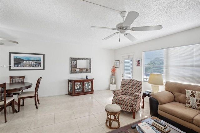 living room with ceiling fan, light tile patterned floors, and a textured ceiling