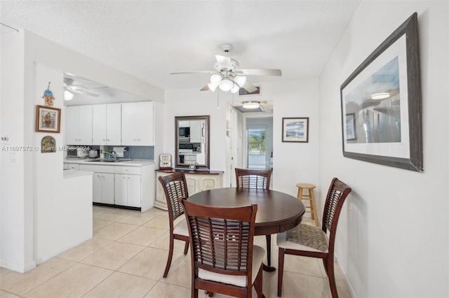 tiled dining area featuring ceiling fan, sink, and a textured ceiling