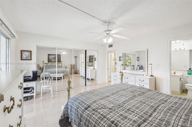 tiled bedroom with ceiling fan, a closet, a textured ceiling, and multiple windows