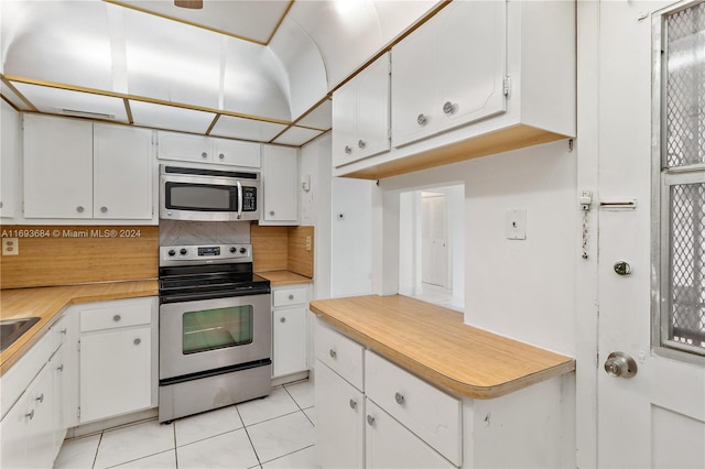 kitchen featuring decorative backsplash, white cabinetry, stainless steel appliances, and light tile patterned floors