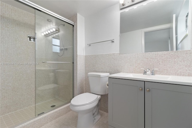 bathroom featuring vanity, a shower with shower door, tile walls, and toilet