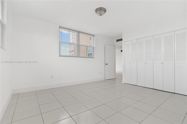 unfurnished bedroom with light tile patterned floors and a closet