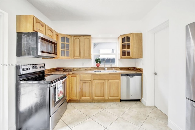 kitchen featuring light tile patterned flooring, appliances with stainless steel finishes, light brown cabinets, and sink