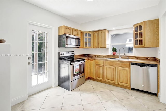 kitchen featuring appliances with stainless steel finishes, light tile patterned floors, and sink